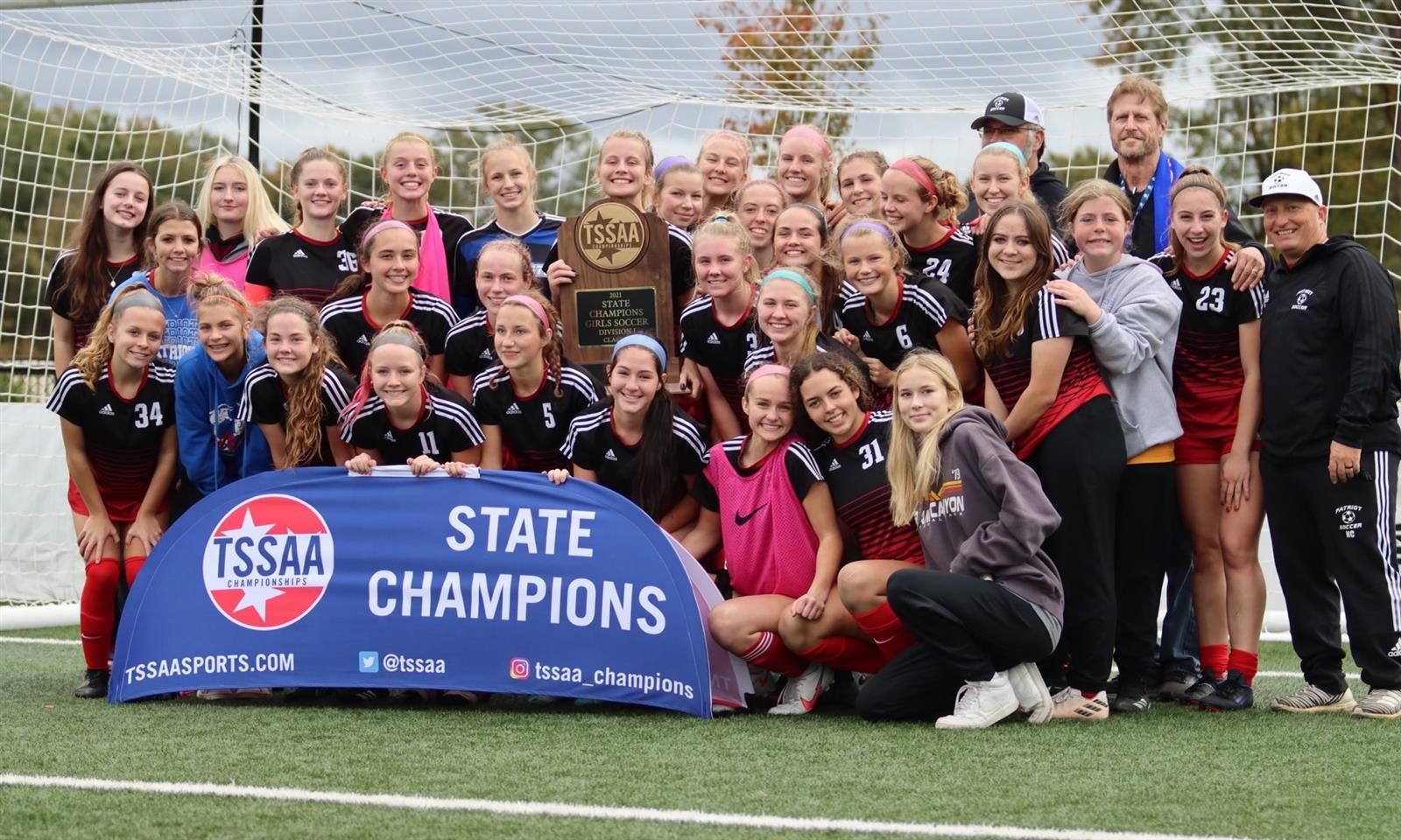 The Page High girls soccer teams smiles while standing behind a group banner